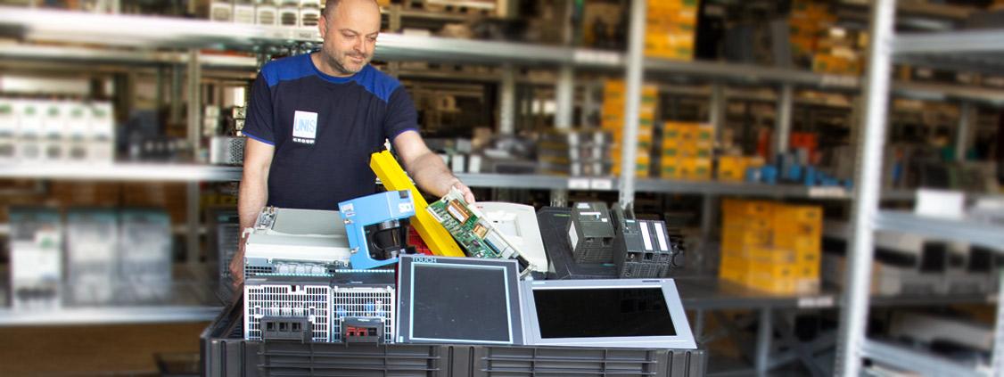 Worker sorting used industrial electronic equipment into a collection bin.